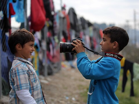 Twee gevluchte kinderen spelen met de camera van een fotograaf.