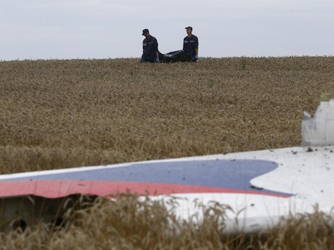 Leden van het Oekraïense 'Emergency Ministry' dragen de stoffelijke resten weg nabij de rampplek van MH17.