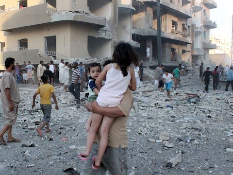 Een man draagt zijn twee kinderen weg van de plek van een explosie in de Syrische stad Raqqa.
