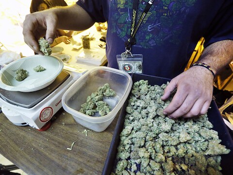Een man verdeelt porties marihuana om op 1 januari te verkopen.