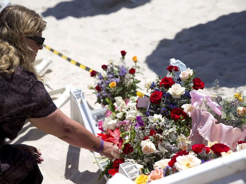 Een vrouw legt bloemen op het strand waar gisteren de aanslag plaatsvond.