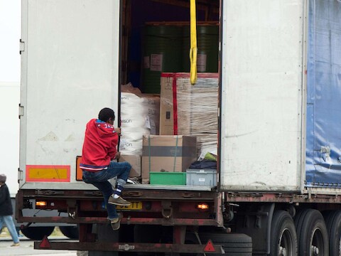Een illegale migrant springt op een vrachtwagen in de haven van Calais.