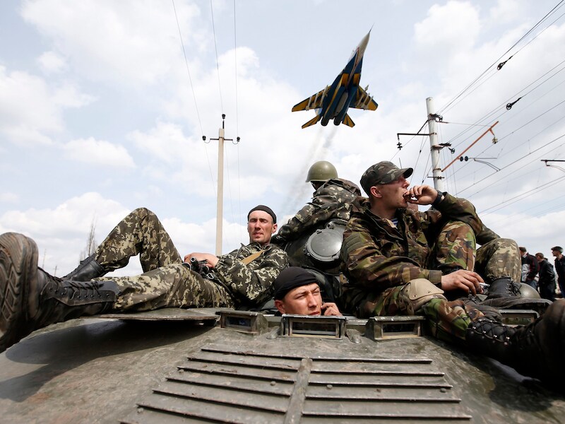 Een gevechtsvliegtuig vliegt boven Oekraïense soldaten.