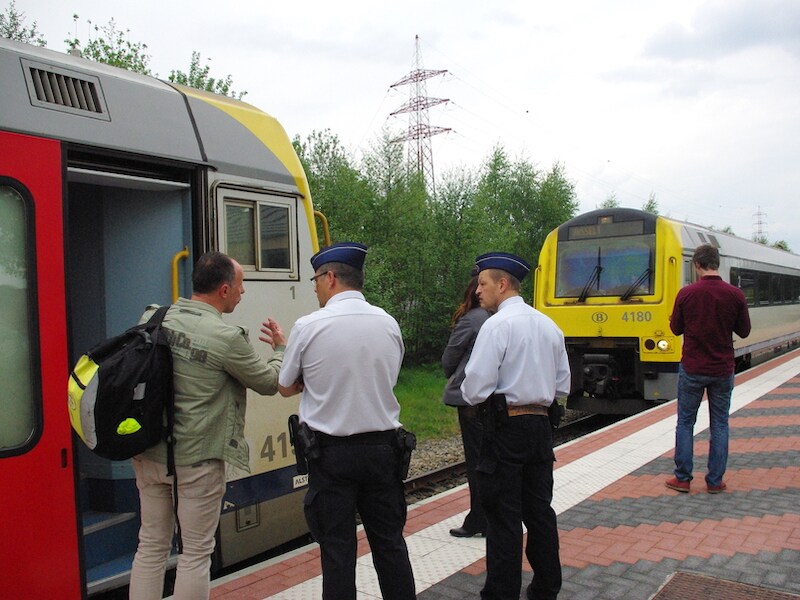 Enkele reizigers vragen de spoorwegpolitie om meer uitleg, terwijl ze wachten tot hun trein verder rijdt.