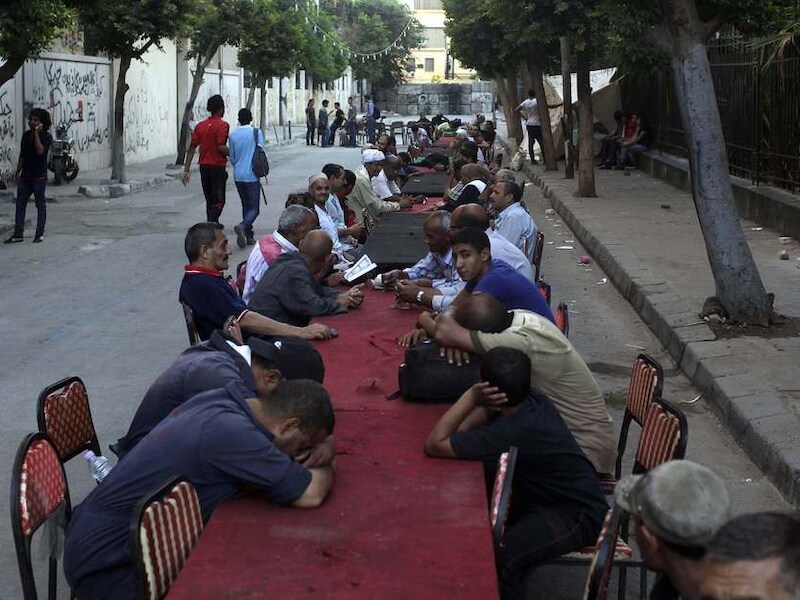 Egyptische moslims zitten in de buurt van het Tahrirplein in Cairo aan lange tafels te wachten tot ze mogen eten volgens de Ramadan.