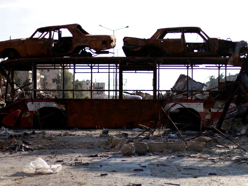 Een uitgebrande bus en auto's worden gebruikt als barricade, nadat regeringstroepen een deel van Aleppo hebben heroverd.