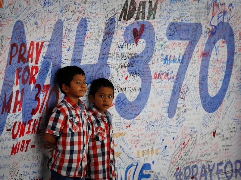 Twee Maleisische kinderen aan een herdenkingsmuur voor de vermiste passagiers van de vlucht MH370. 