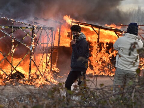 Te ontruimen barakken werden in brand gestoken door de migranten om de politieactie te vertragen.