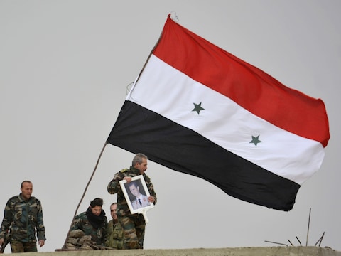 Strijders loyaal aan president Bashar al-Assad tonen zijn portret in de zuidelijke Syrische stad Deir-al-Adas.