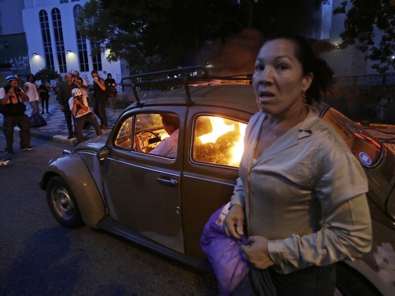 Een auto in São Paulo vloog in brand toen de bestuurder een brandende barricade probeerde te passeren die door betogers was opgericht. De vrouw op de foto zat ook in de auto, maar wist te ontkomen.