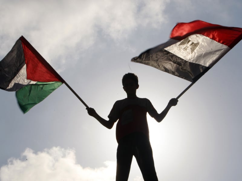 Een Palestijn zwaait met een Egyptische en een Palestijnse vlag in Gaza-stad.