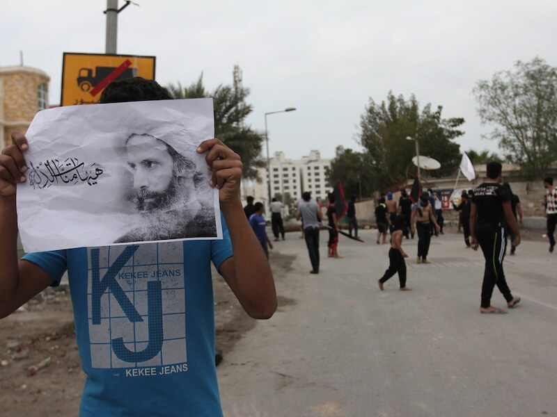 Een demonstrant houdt een foto van Nimr al-Nimr omhoog.