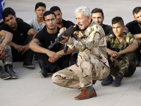 Een aanhanger van het sjiitische Mehdi-leger geeft schietles aan nieuwe rekruten, die zullen worden ingezet in de strijd tegen het soennitische ISIS.