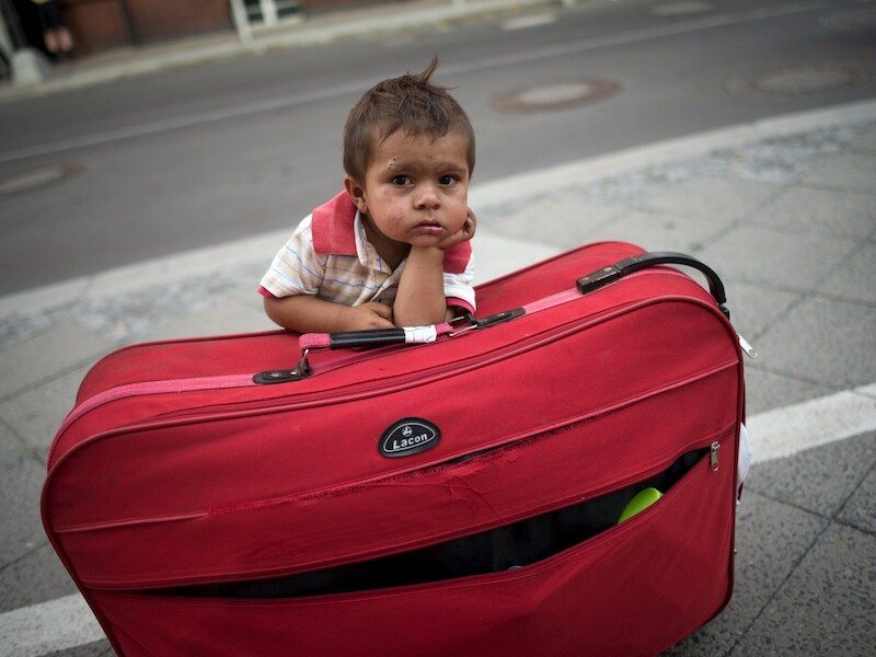 Een jongen wacht bij de bagage op zijn ouders in het treinstation van Berlijn.
