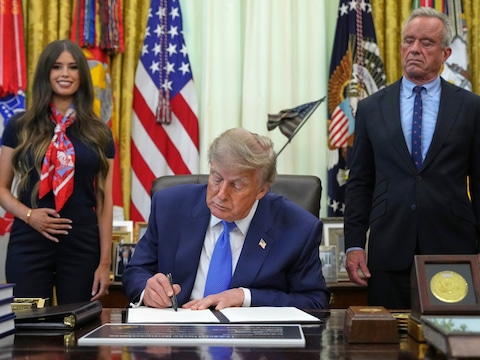 President Donald Trump ondertekent een presidentieel decreet over vaccins, terwijl Jayme Franklin (links) en minister van Volksgezondheid en Sociale Zaken Robert F. Kennedy Jr. toekijken (rechts).