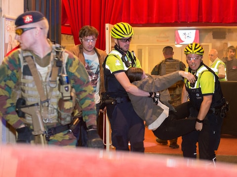 Een slachtoffer wordt uit de zaal gered terwijl een militair de wacht houdt.
