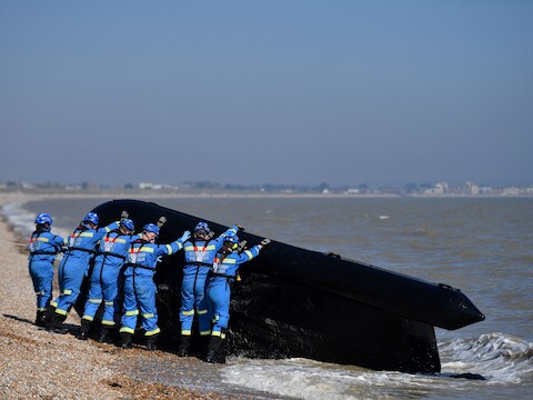 Leden van de kustwacht in Engeland halen een boot uit het water waarmee migranten het Kanaal van Frankrijk naar Engeland probeerden over te steken.