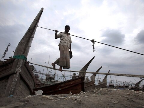 Een visser in Bangladesh maakt zijn vissersboot vast aan de oever van Kornofuli in Chittagong, Bangladesh