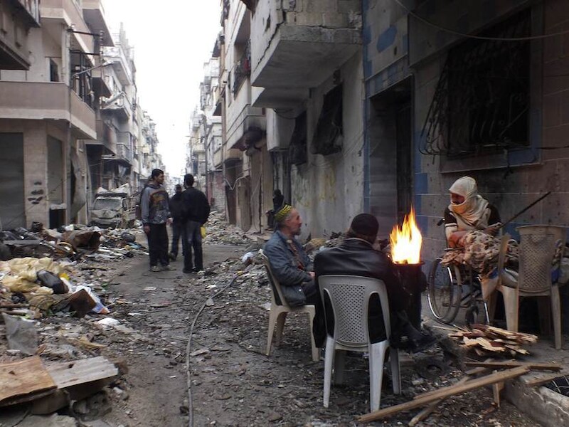 Inwoners van Homs houden zich warm rondom een vuur in een van de belegerde wijken van de stad.