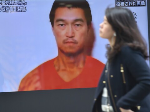 Een vrouw wandelt voorbij een tv-scherm in Tokio waarop de Japanese journalist Kenji Goto staat.