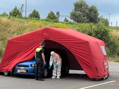 Een agent en een medewerker van het labo onderzoeken een wagen aan de site van nachtclub Ikon.