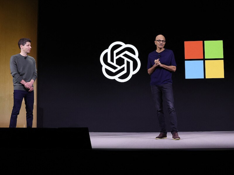 De bazen van OpenAI en Microsoft samen op het podium van een persconferentie.