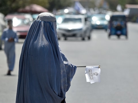 Een Afghaanse vrouw in een boerka verkoopt taliban-vlaggen tijdens de viering van het vijfjarig bestaan ​​van de taliban-regering na hun terugkeer aan de macht, 15 augustus.