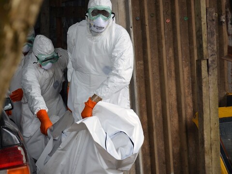Medewerkers van het Rode Kruis in Liberia dragen beschermende pakken als ze het lichaam van een overleden ebola-patiënt wegdragen.