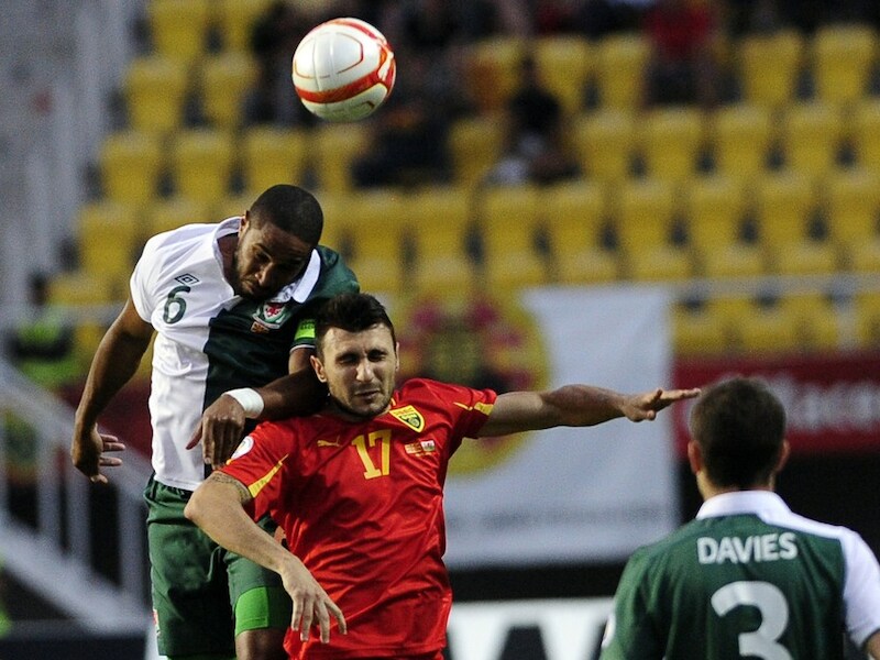 Ashley Williams met Wales in een luchtduel met de Macedoniër Jovan Kostovski, spits van OH Leuven.