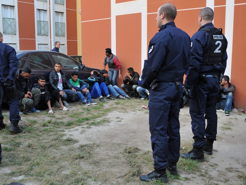 Franse politiemannen bij Tunesische vluchtelingen die tijdens een raid werden opgepakt.
