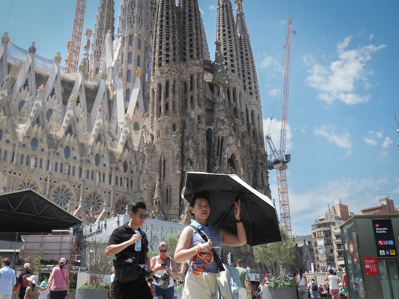Toeristen trotseren de hitte aan de Sagrada Familia in Barcelona.