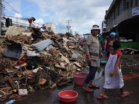 Inwoners van Tacloban lopen langs de puinhopen van tyfoon Haiyan.