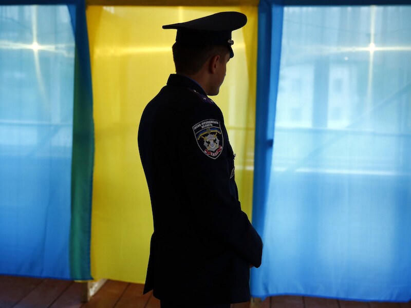 Een Oekraïnse politieagent voor enkele stemhokjes in het de provincie Ivano-Frankivsk Oblast.