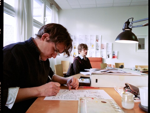 Laurent Sourisseau (Riss) (links) aan het werk op de redactie van Charlie Hebdo. Foto uit 2012.