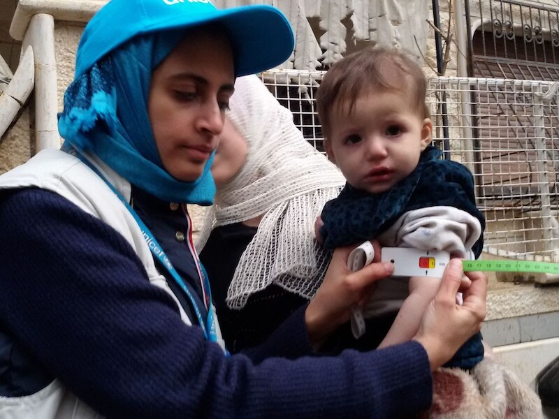 Een UNICEF-medewerker meet de armomtrek van een kind in Madaya om te kijken of hij ondervoed is. Volgens één hulpverlener geven ouders hun kinderen slaappillen om het hongergevoel te onderdrukken.