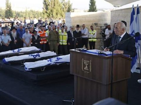 De Israëlische president Peres spreekt bij de herdenkingsbijeenkomst voor de drie jongens voor ze begraven worden.