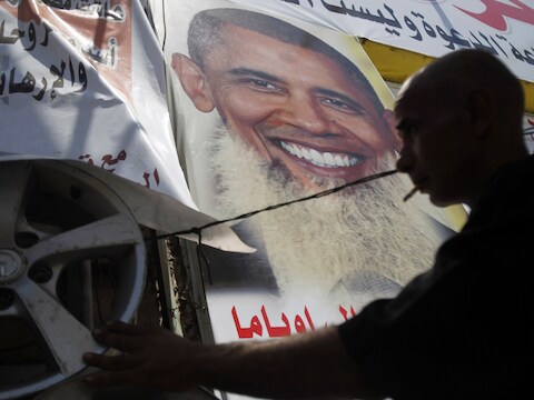 Een demonstrant hangt posters op van Obama met lange baard, om een statement te maken tegen de relatie tussen de VS en Egypte.