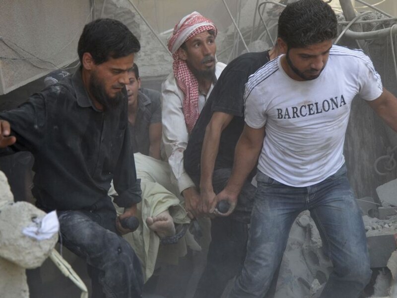 Een gewonde Syriër wordt weggedragen na een luchtaanval in de buurt van Damascus.