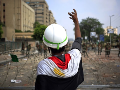 Een aanhanger van Mursi maakt gebaren richting Egyptische soldaten die het hoofdkwartier van de Republikeinse Garde in Caïro bewaken.