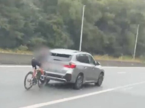 Een wielrenster van SD Worx-Protime rijdt achter een BMW op de R8 in Kortrijk.