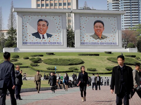 Noord-Koreanen wandelen langs portretten van voormalige leiders Kim Il-sung en Kim Jong-un in een park in Pyongyang.