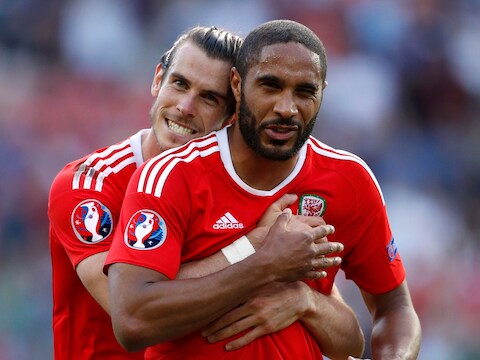 Ashley Williams wordt geknuffeld door Gareth Bale na de gewonnen achtste finale tegen Noord-Ierland.