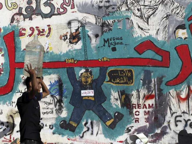Een Egyptenaar loopt langs een wand vol anti-Morsi-graffiti.
