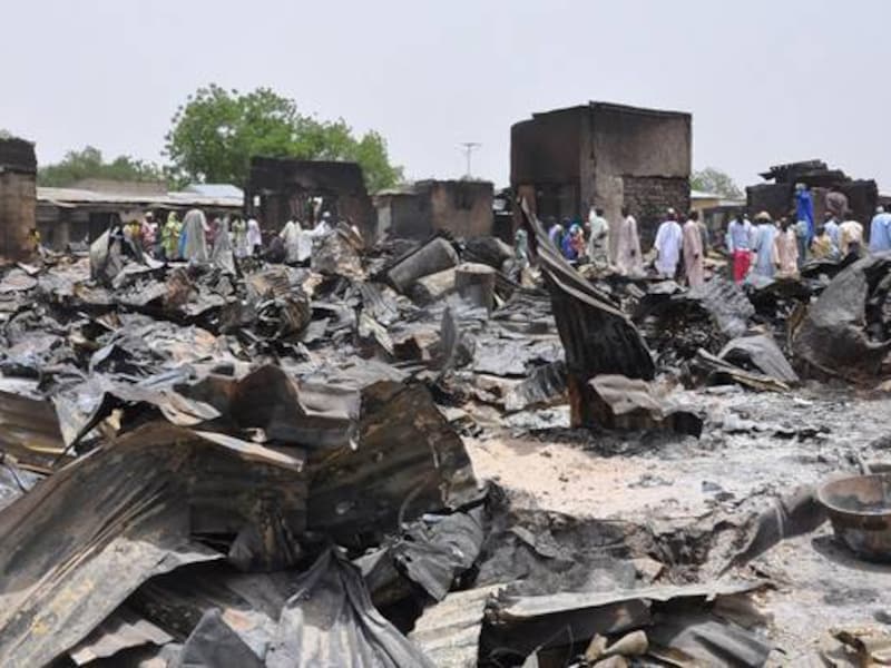 Mensen lopen tussen de door Boko Haram verbande huizen in Gambaru, Nigeria.