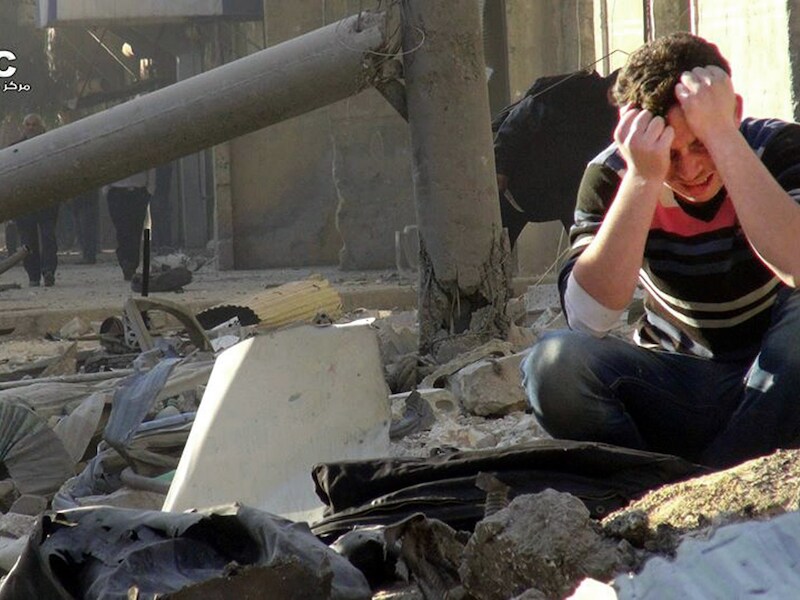 Een jongen in Aleppo huilt op de resten van een gebouw dat is geraakt door een zogeheten "vatenbom".