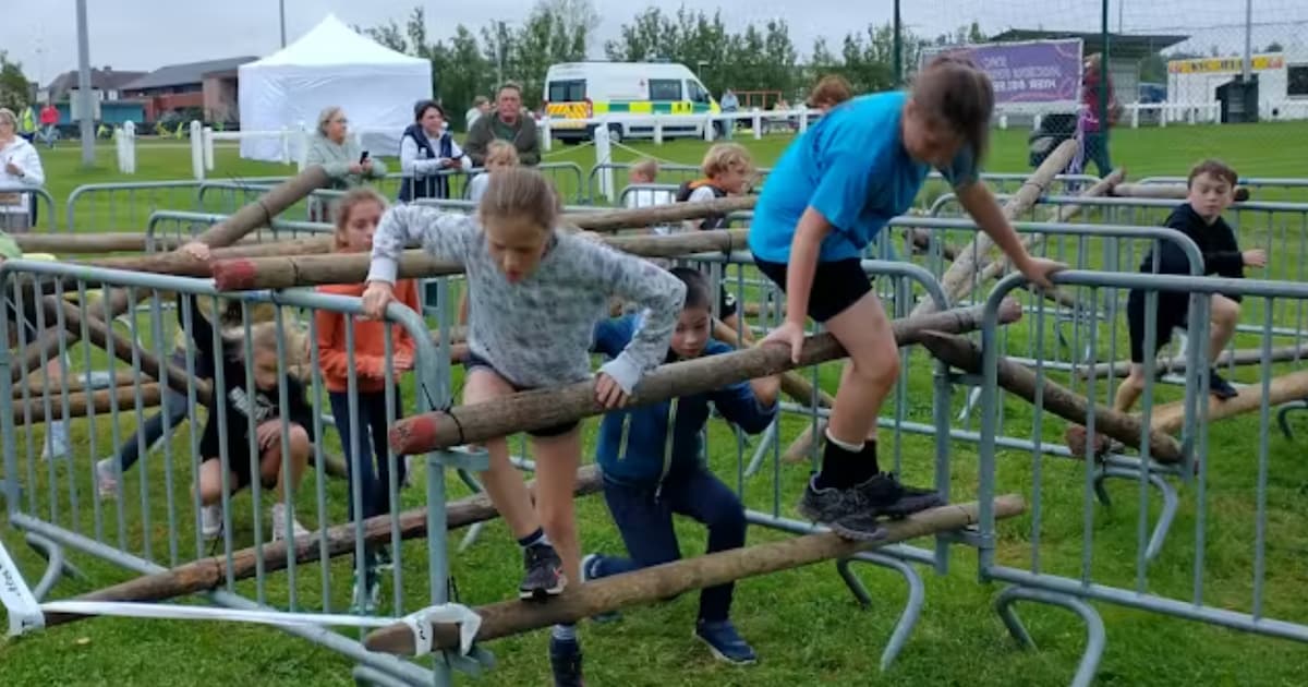 Leerlingen springen, klimmen en kruipen tijdens hindernissenloop op de Kerkakkers