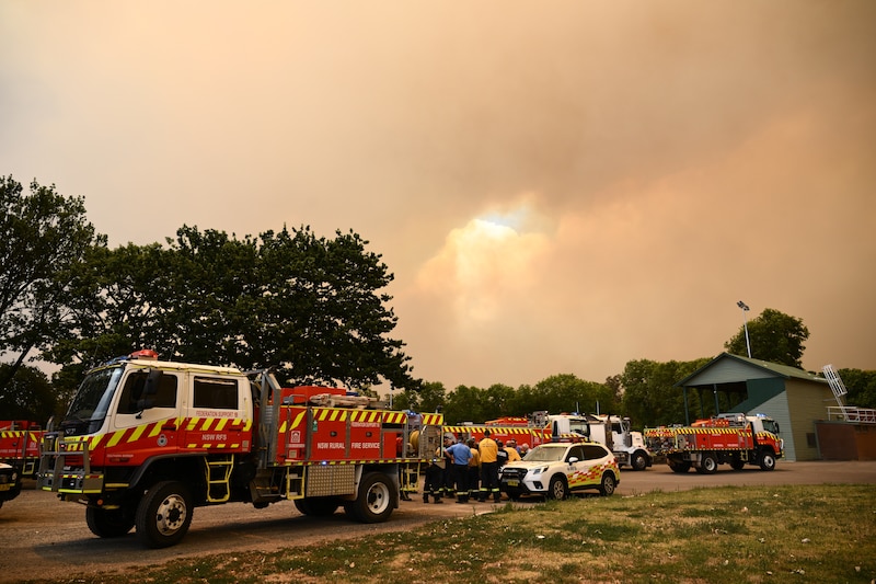 Los bomberos se preparan mientras las nubes de humo se elevan desde el incendio forestal cerca de Longwood.