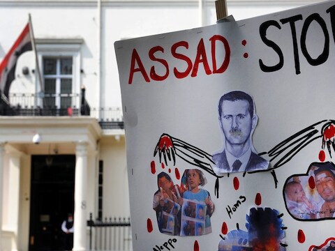 Protestanten tonen een anti-Assad-bord aan de Syrische ambassade in Londen.