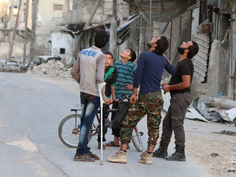 Beducht voor luchtaanvallen speuren mannen de lucht af in het door rebellen gecontroleerde deel van Aleppo.