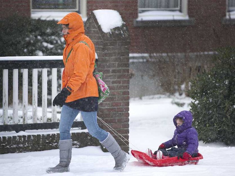 Een vrouw met een slee baant zich een weg door de sneeuw in Heerlen.
